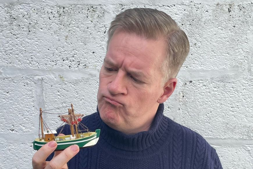 Man looking confused, holding a little boat